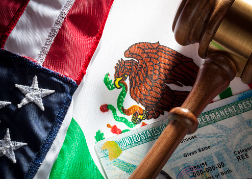 Mexican flag and USA flag and gavel and green card. Immigration concept.