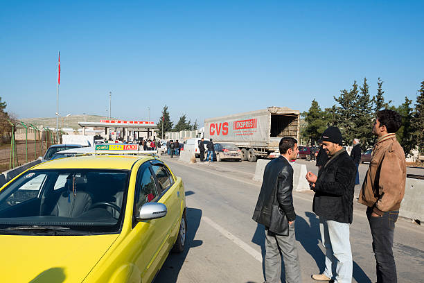 Atmeh, Syria - January 14, 2013: Men stand outside a taxi on the Syrian side of the Bab al-Hawa border crossing between Turkey and Syria.