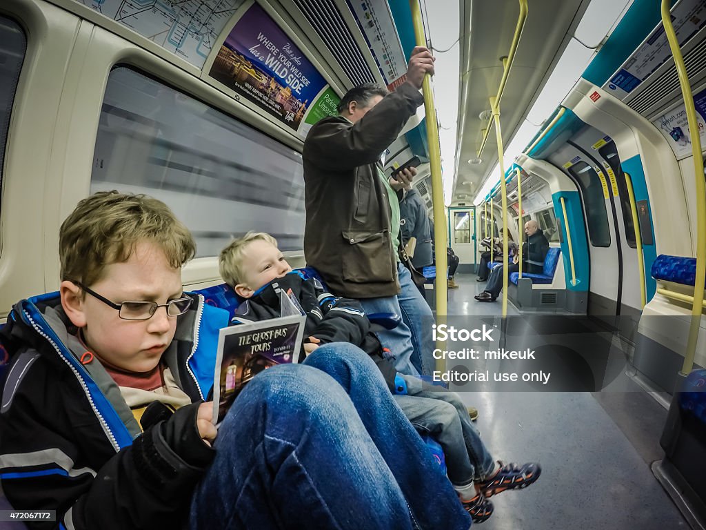 Passengers on a London Underground subway train London, United Kingdom - January 3, 2015: Passengers on a London underground commuter train. Shows a young boy reading a subway train map and other children and adults sleeping or reading as they travel to their destinations. London - England Stock Photo