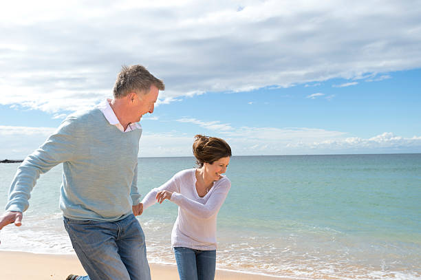 istock Happy mature couple running along the beach 472067661