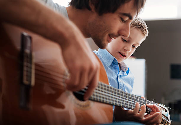 Father teaching son Guitar Father teaching his son how to play Guitar. father and son guitar stock pictures, royalty-free photos & images