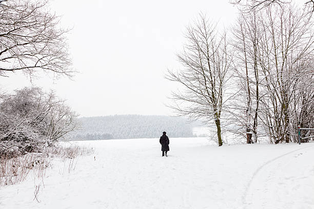 istock winter snow landscape woman in black walking 472067977