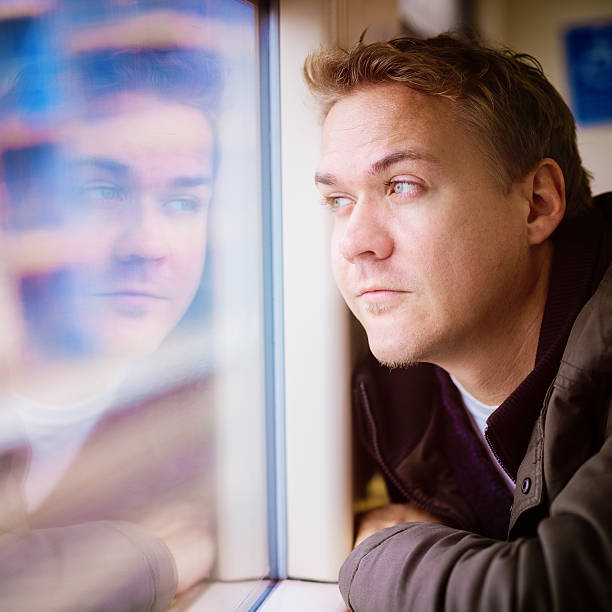 istock Pensive young man looking out of a train window 472068553