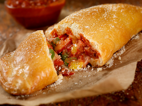 Authentic Hand Made Italian Calzone with Pepperoni, Sausage, Peppers, Fresh Parmesan and Marinara Sauce  - Photographed on a Hasselblad H3D11-39 megapixel Camera System