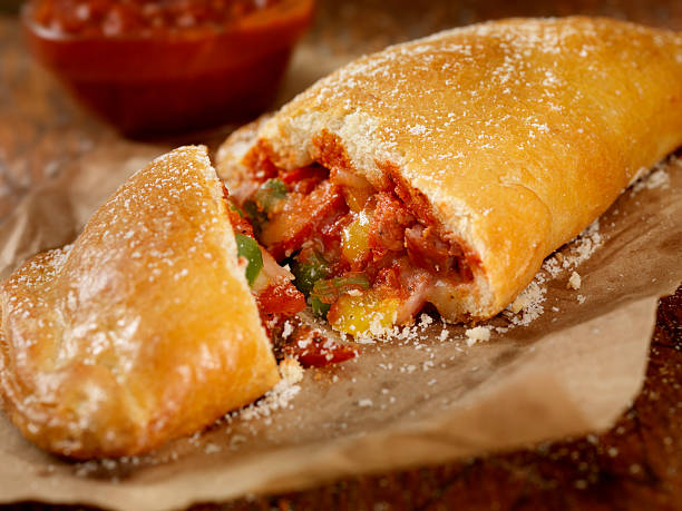 Calzone Authentic Hand Made Italian Calzone with Pepperoni, Sausage, Peppers, Fresh Parmesan and Marinara Sauce - Photographed on a Hasselblad H3D11-39 megapixel Camera System Calzone stock pictures, royalty-free photos & images