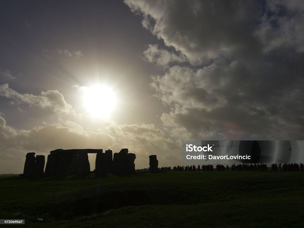 Stonehenge Silhouette Silhouette of Stonehenge, prehistoric monument, on a cloudy autumn day. In background are tourists in line enjoying the bright side of monument. The Silhouette of people is too small and dark to recognizable. Amesbury - England Stock Photo