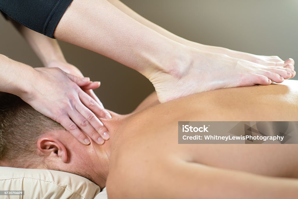 Ashiatsu Neck Massage A massage therapist massaging a male client's back and neck. Adult Stock Photo