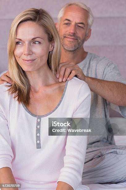 Uomo Sorridente Dando Un Massaggio Alla Moglie - Fotografie stock e altre immagini di Accudire - Accudire, Adulto, Adulto di mezza età