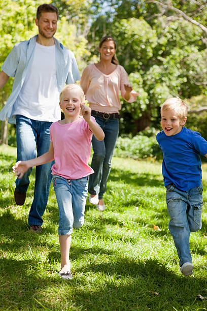 istock Smiling siblings running while being followed by their parents 472070859
