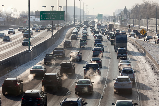 Denver, Colorado, U.S.A. - December 6, 2013: Multiple lanes of traffic crawl slowly on southbound Interstate-25 as exhaust fumes rise into the air on cold winter day.