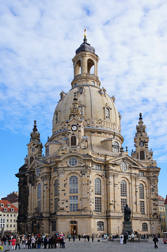 Dresden, Germany - September 23, 2012: Tourists walk alongside of the Dresden Frauenkirche, a Lutheran Baroque church built in the 18th century and reconstructed in 2005, lead of the architectural ensemble of the Neumarkt, in the cloudy autumn afternoon.