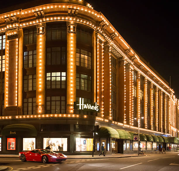 Harrods department store. Ferrari passes in front of the buildin London, United Kingdom - November 11, 2013: Harrods department store. Facade illuminated at night. Ferrari passes in front of the building harrods photos stock pictures, royalty-free photos & images