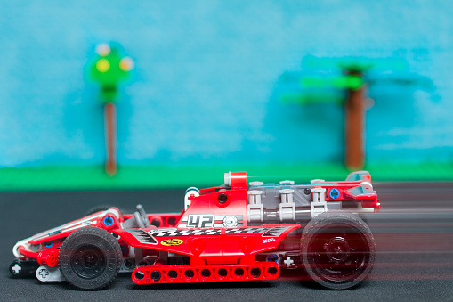 brugstraat, Aalter, Belgium - december 01th 2013: Lego tachnics race car in moition. Displayed on a black underground and sky background with 2 trees of lego. Shot in home studio. focus on the race car 
