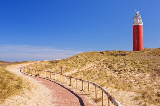 A footpath leading towards the lighthouse of the island of Texel in The Netherlands on a sunny day.