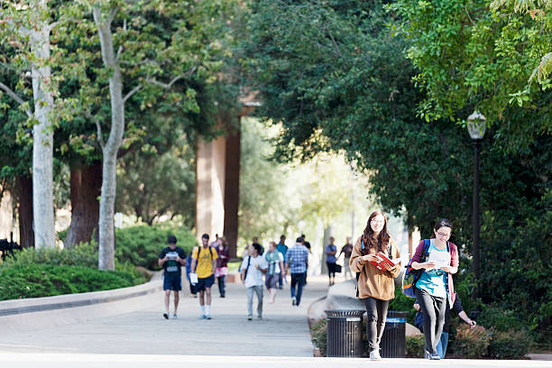University of California, Los Angeles Los Angeles, California, USA - June 13, 2012. The location is University of California, Los Angeles. Two Asian female students are walking in the foreground. A larger group of students are walking in the background. ucla photos stock pictures, royalty-free photos & images