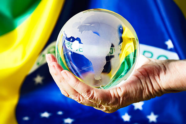 istock Fortune teller's hand holds glass globe against Brazilian flag 472079003