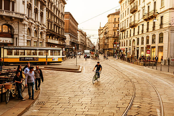 Milan, Italy - September 29, 2011: Street of Milan with moving tram and people. Young man cycling along the street. 