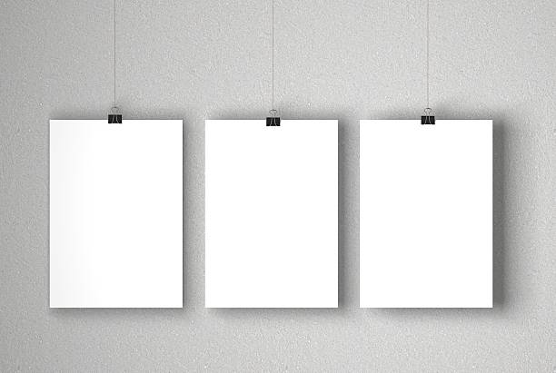 Blank white posters A blank white posters suspended against a grey concrete wall. The paper is being held by a paper clip which is hanging on a piece of string. Light is coming from the left of the image which casts a soft shadow onto the background. The paper is ready for you to add your own designs and artwork. portfolio photos stock pictures, royalty-free photos & images