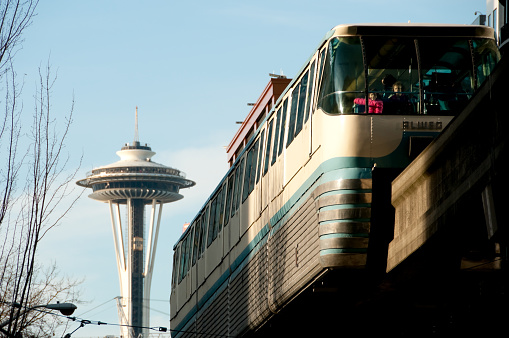 Seattle, USA - November 24, 2013: People traveling on the Seattle Monorail on fifth avenue in downtown seattle late in the day with the Space Needle in the background. The Seattle monorail and Space Needle are two of the iconic tourist attractions from the Worlds Fair from 1962.   