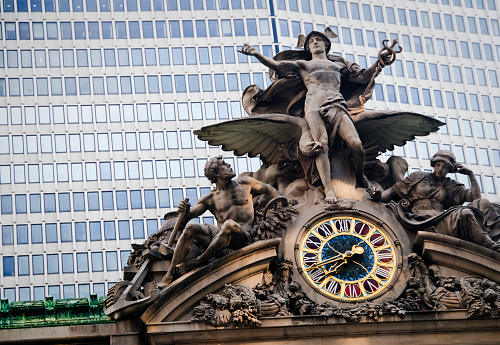 New York, USA - June 27, 2010: The statue of Mercury (Hermes) with a clock above the Grand Central Station with a modern office building in the background, Manhattan, New York City.  Focus on clock face.