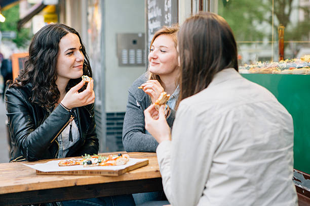 istock three woman sit together in a resaurant and eat pizza 472082266