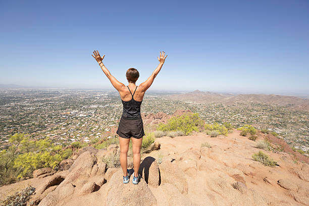 Mature woman conquering mountain climb - leadership