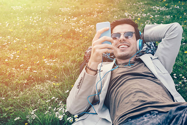 istock Young man texting on smartphone in the grass 472082502