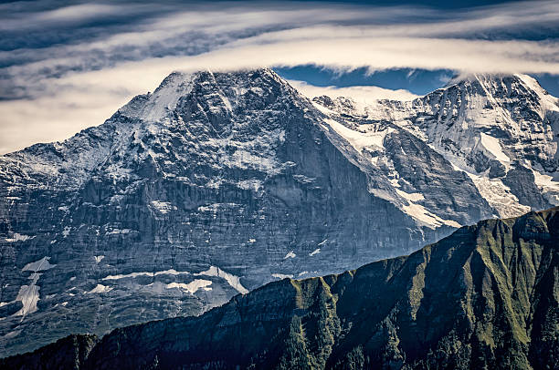 Mountains in Bernese Alps: Eiger and Mönch Mountains in Bernese Alps, Switzerland. The Eiger is a 3,970 metres (13,020 ft). The Mönch (German: "monk") 4,107 m (13,474 ft).  eiger northface stock pictures, royalty-free photos & images