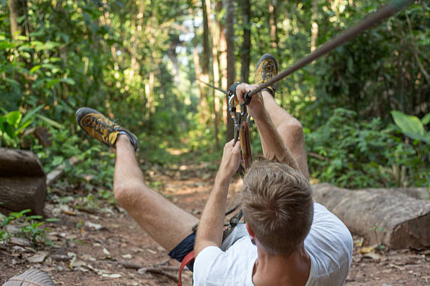 junger mann genießen sie in den seilpark im wald - ziplining zip line outdoors zip lining stock-fotos und bilder