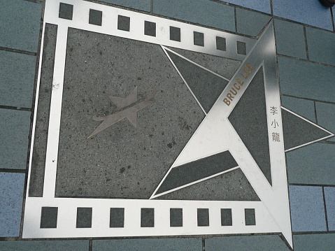 Hong Kong, China – December 31, 2008: Bruce Lee plaque. Plaques honoring celebrities, directors, opera-stars and scriptwriters of Hong Kong movies on the ground at the Avenue of Stars, Hong Kong. Many tourists come to visit the Tsim Sha Tsui Promenade (Avenue of the Stars). The Avenue of Stars is located along the Victoria Harbor in Hong Kong.