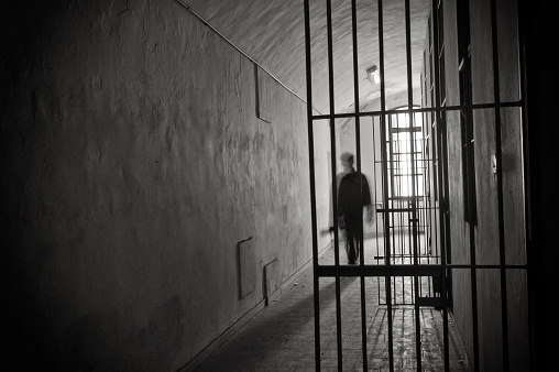 Silhouette of an inmate on prison's cell door.