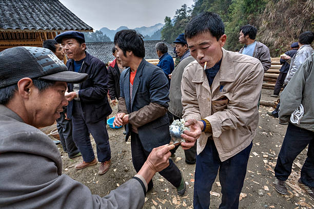 Langde Village, Guizhou, China - April 16, 2010: Asian people take rice hands on a rural celebration.