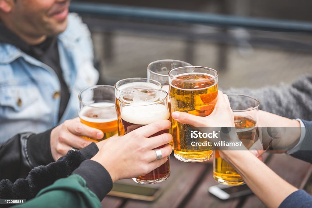 Group of friends enjoying a beer outside a pub in London Group of friends enjoying a beer at pub in London, toasting and laughing. They are four girls and two boys in their twenties. Beer - Alcohol Stock Photo