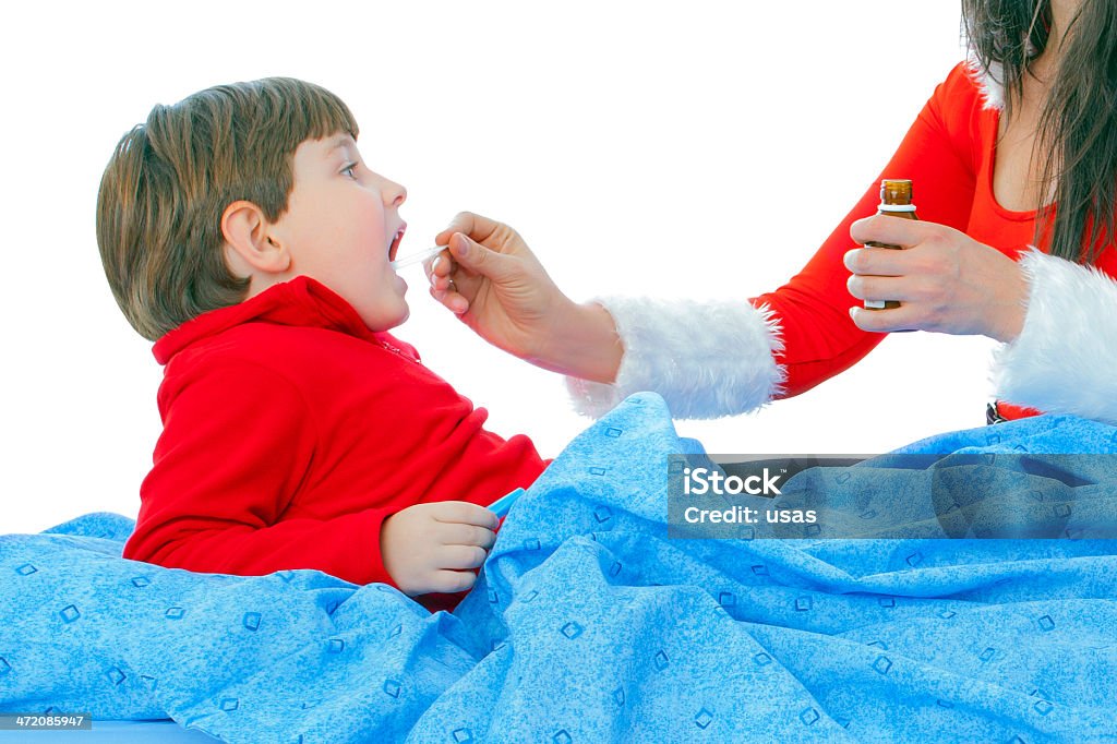 Red costume wore Women giving syrup to ill boy Christmas time, 6-7 Years Stock Photo