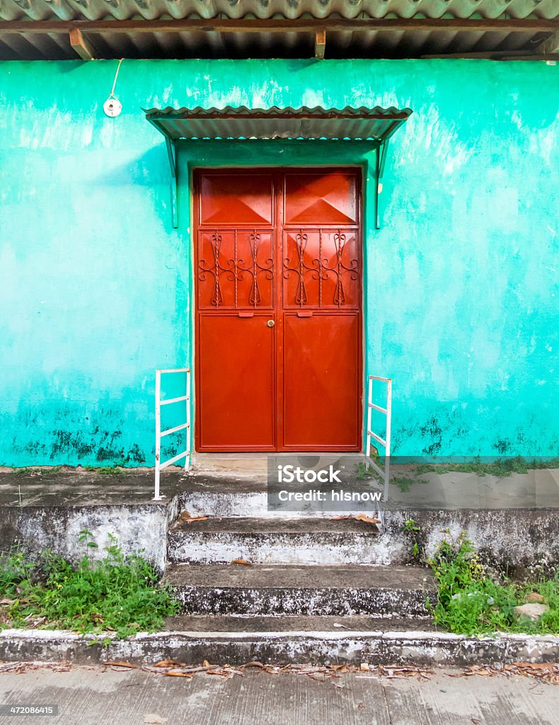 Red Door on Turquoise Stucco Home Blue green stucco home and red decorative metal front door; traditional central, south, latin America home in rural area. El Salvador Stock Photo