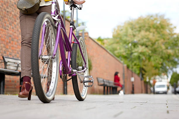 Low section image of woman walking with a bicycle on sidewalk