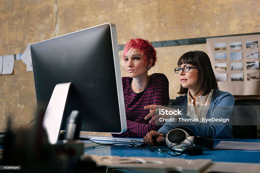 Businesswomen collaborating while working on computer Two women collaborating on a new business idea. The woman are sitting around one computer working together.  25-29 Years Stock Photo