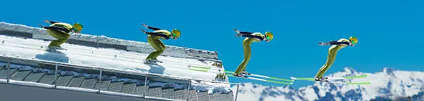 Multiple image of young male ski jumper during the take off against the blue sky