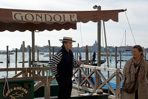 Venice, Italy - October 13, 2013: In italian Gondoliere at his pier in Venice, a woman passing, in October 2013.