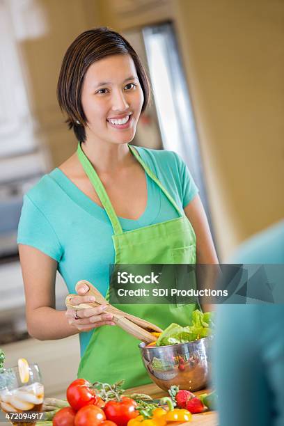 Foto de Jovem Sorridente Mulher Asiática Preparar Salada Na Cozinha e mais fotos de stock de 20 Anos