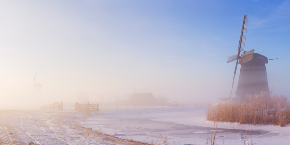 Traditional Dutch windmills on a beautiful frosty and foggy morning.
