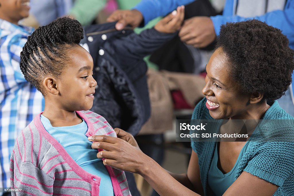 Madre aiutando Sua figlia trovare capi di abbigliamento invernali di unità - Foto stock royalty-free di Afro-americano