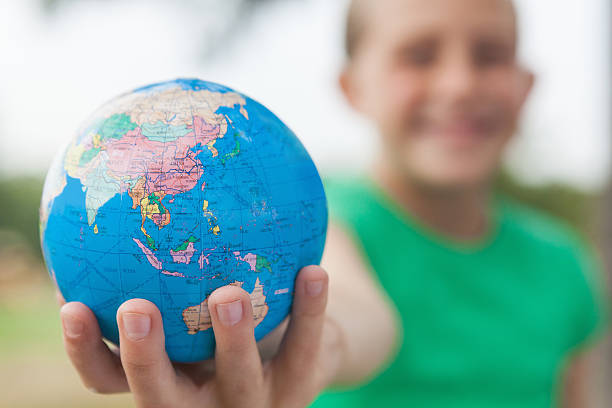 istock Little girl holding world globe in hand; selective focus 472095885