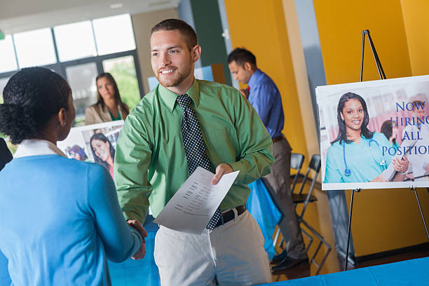Professional man shaking hands with executive at job fair event Professional man shaking hands with executive at job fair event job fair photos stock pictures, royalty-free photos & images