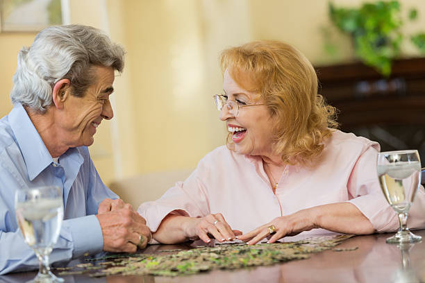 istock Husband and wife laughing together while doing puzzle at home 472096135