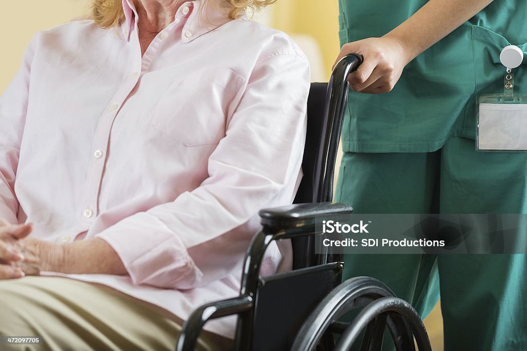 Enfermera pusing paciente de edad avanzada en silla de ruedas, centrarse en las manos - Foto de stock de 70-79 años libre de derechos