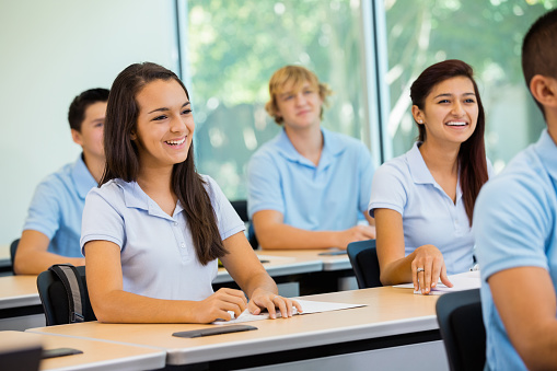 Diverse high school students wearing uniforms in classroom
