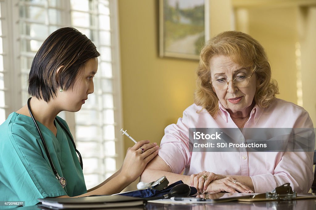 Senior mujer recibiendo la inyección de su personal de enfermería de atención médica - Foto de stock de Doctora libre de derechos