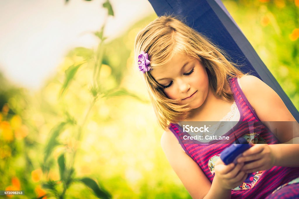 Belle petite fille à envoyer des SMS sur téléphone portable - Photo de 8-9 ans libre de droits