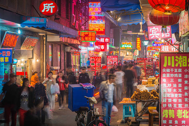 Beijing, China - 28th September 2013: Colourful neon signs illuminating the narrow hutong alleyways of a night market crowded with shoppers and tourists in the heart of Beijing, China's vibrant capital city.